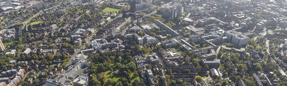Aerial shot of the University of Leeds campus building on a sunny day with green trees surrounding it