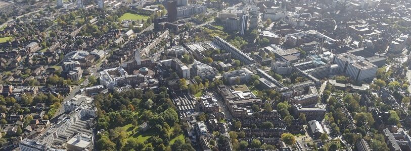 Aerial shot of the University of Leeds campus building on a sunny day with green trees surrounding it