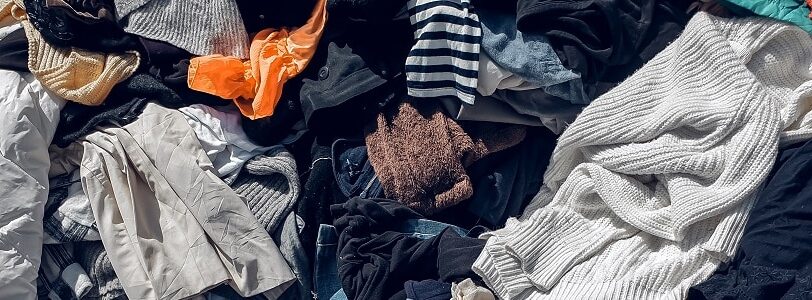 An assortment of used clothes left in a pile, provoking the question; Is sustainable fashion really sustainable?